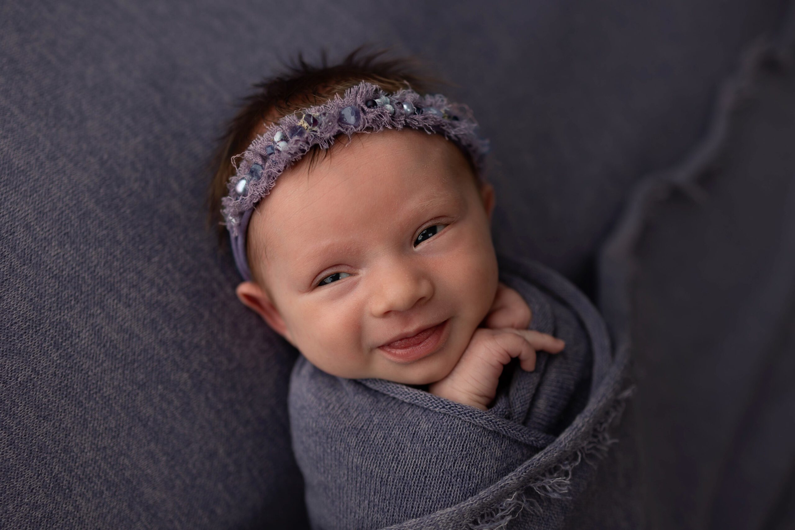 smiling newborn girl on purple background
